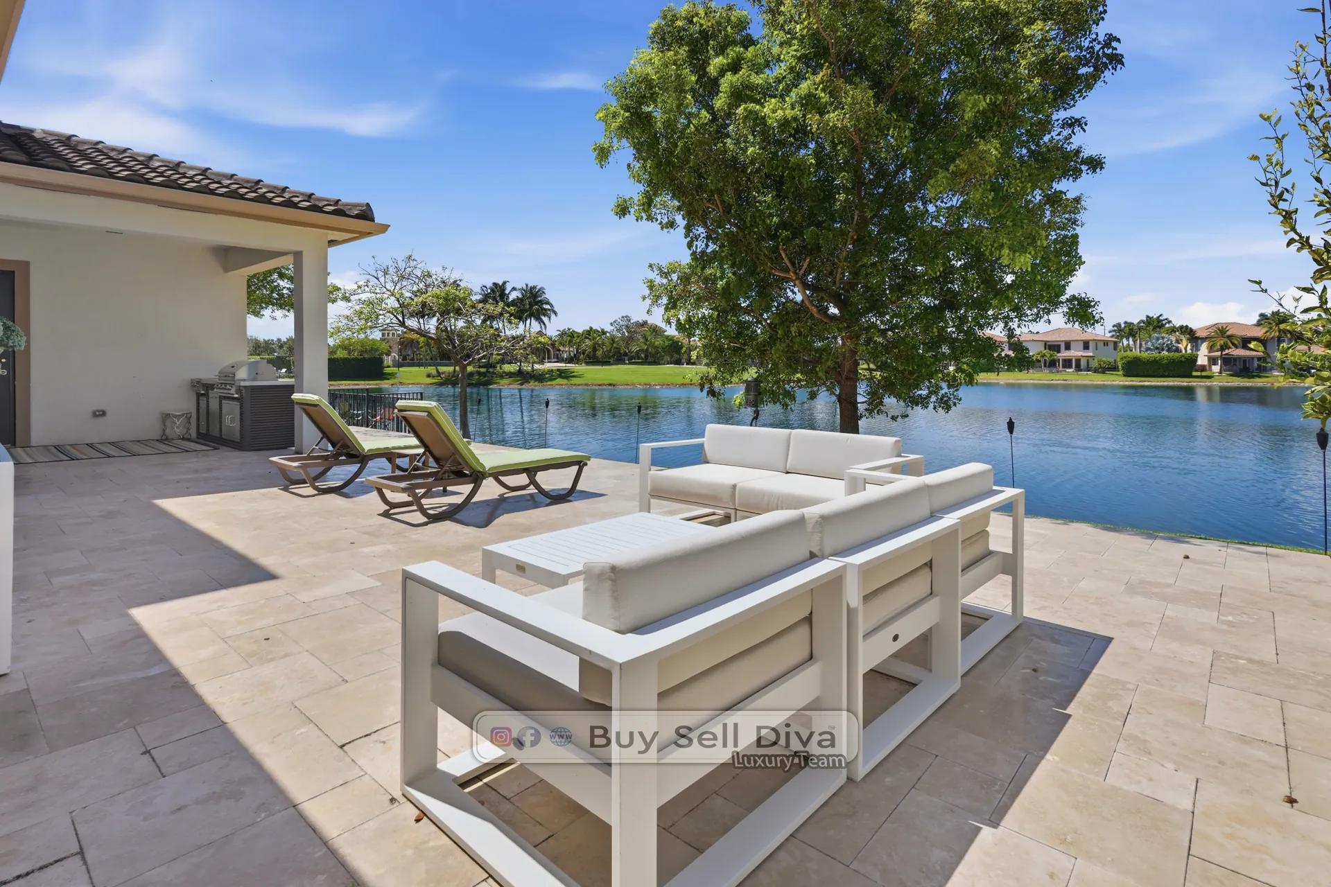 Lakefront estate home in Parkland Florida: travertine patio with direct water view and outdoor seating